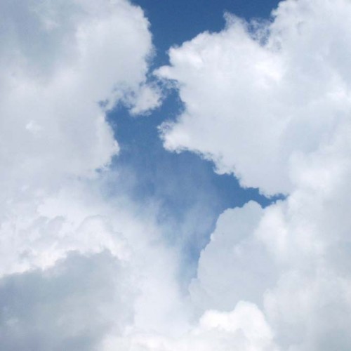Blue sky with white and gray clouds forming patches and gaps overhead