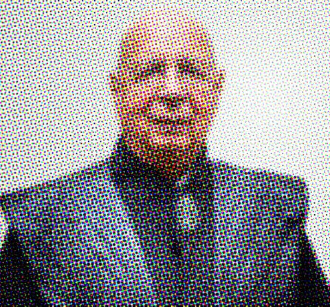 Pixelated portrait image of a person wearing glasses and dark clothing against a light background