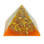 Orange and yellow orgonite pyramid with metallic shavings embedded in clear resin, viewed from front angle