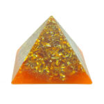 Pirámide orgonite de resina naranja y transparente con virutas metálicas doradas incrustadas, fotografiada sobre fondo blanco