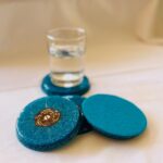 Dessous de verre orgonite bleus tachetés avec spirale dorée, un debout, un couché, avec verre transparent sur base bleue