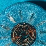 Circular dark glass spiral plate with metallic specks on blue textured surface with clear crystal points around edges