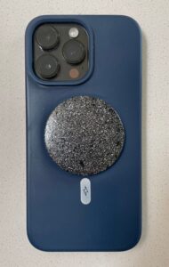 Blue silicone phone case with triple camera cutout, circular black glittery disc attached, white lightning bolt symbol below