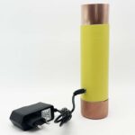 Yellow cylindrical device with copper-colored metal ends and black power adapter with cord on white background