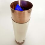 Vara cilíndrica de cobre y blanca con cristal triangular azul visible en la sección superior de cobre, vista en ángulo