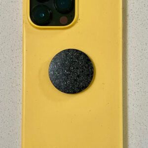 Yellow phone case with triple camera cutout, black circular disc with sparkly texture attached to back center