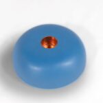 Blue spherical orgonite candle holder with copper-colored metal insert in center hole, viewed from above on white background