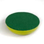 Round green and yellow sponge with abrasive green top surface and yellow foam base, viewed from above at slight angle