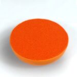 Orange circular orgonite disc with textured surface, viewed from above at slight angle against white background