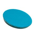 Oval blue orgonite disc with smooth surface and textured metallic edge, viewed at slight angle on white background