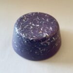 Cúpula orgonite púrpura translúcida con espirales metálicas y virutas incrustadas visibles en la superficie de resina