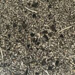 Dark circular pendant with silver-colored metal and black shungite particles visible on speckled ground surface