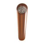 Copper-colored cylindrical tube viewed from above at angle, showing gray crystalline orgonite material inside the open top end