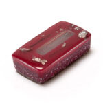 Red rectangular orgonite brick with gold flecks, clear crystal visible on top surface, glossy finish, viewed from above at angle