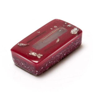Red translucent rectangular brick with gold flecks, smooth glossy top surface, textured bottom, viewed at angle on white background