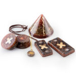 Various orgonite items including pyramid, circular discs with crosses, rectangular pieces with crosses, and pendant on cord