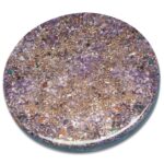 Circular purple orgonite disc with embedded crystals, metal shavings, and colorful stone fragments on white background