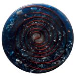 Round blue orgonite disc with red spiral pattern and embedded metal shavings, viewed from above