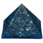 Blue translucent orgonite pyramid with embedded metallic fragments and wire coils, viewed at angle against white background