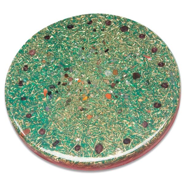 Round green orgonite charging plate with embedded crystals, stones, and metallic flecks viewed from above on white background