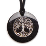 Round black shungite pendant with silver tree of life design, hanging from black cord against white background