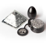 Klare Pyramide, schwarzes Ei, zylindrisches Objekt mit gefleckter Oberfläche und schwarze Scheibe mit Baumsymbol