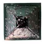 Square green-framed pyramid with metallic silver flakes and black shungite pieces embedded in clear resin, viewed from above